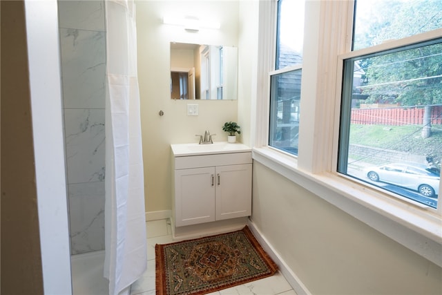 bathroom with tile patterned flooring, vanity, and tiled shower