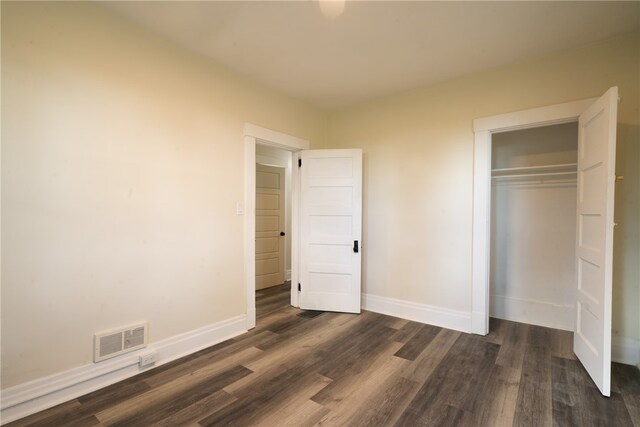 unfurnished bedroom featuring a closet and dark wood-type flooring