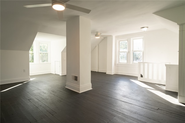 bonus room featuring ceiling fan, decorative columns, and dark wood-type flooring