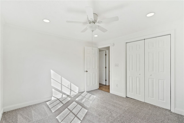 unfurnished bedroom with ceiling fan, a closet, light carpet, and ornamental molding