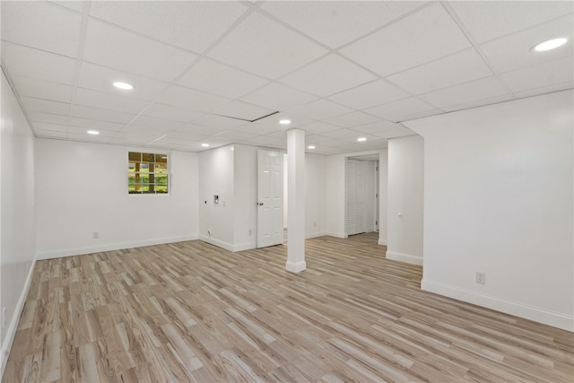 basement with a paneled ceiling and light hardwood / wood-style floors