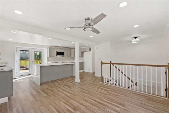 unfurnished living room featuring light hardwood / wood-style flooring, ceiling fan, a textured ceiling, and ornamental molding