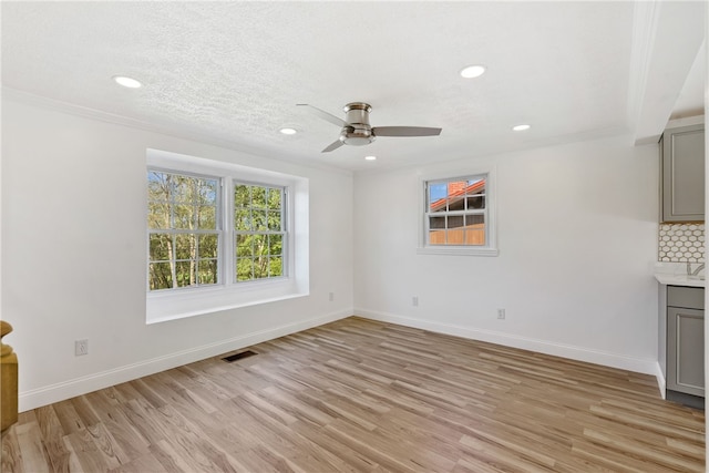 interior space featuring light hardwood / wood-style flooring, a textured ceiling, ceiling fan, and crown molding