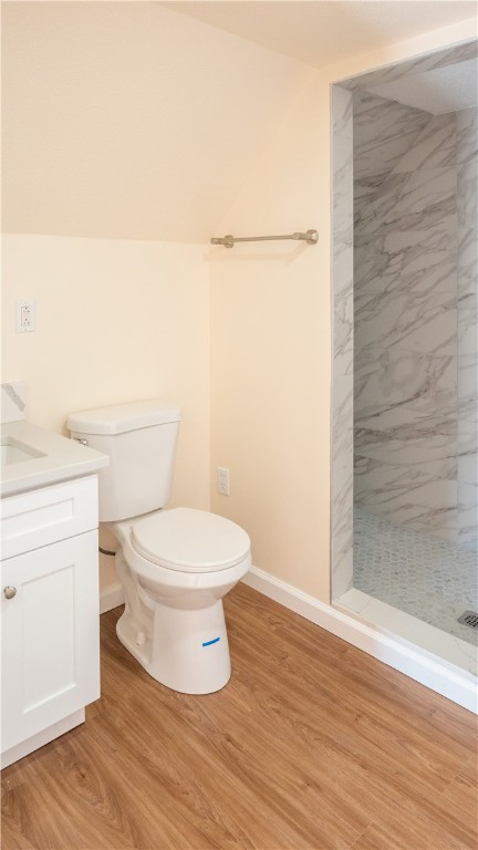 bathroom featuring a tile shower, vanity, toilet, and hardwood / wood-style flooring