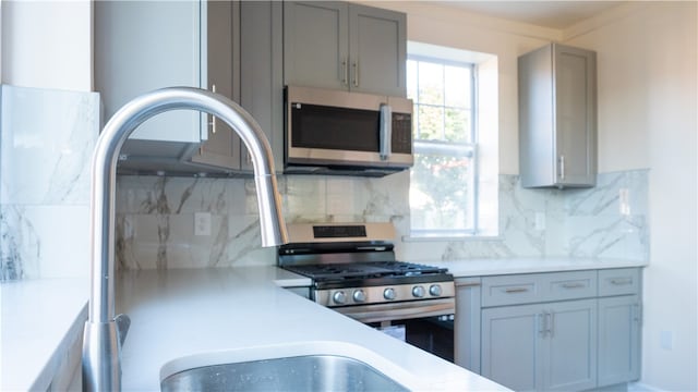 kitchen with gray cabinets, appliances with stainless steel finishes, sink, and tasteful backsplash