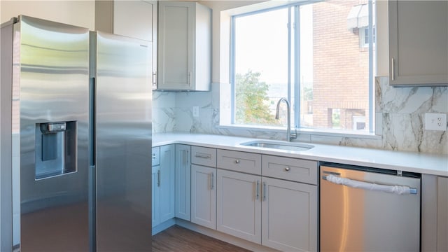 kitchen with gray cabinetry, stainless steel appliances, decorative backsplash, and sink