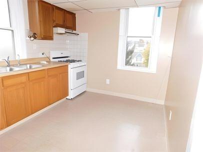 kitchen featuring a paneled ceiling, sink, decorative backsplash, white gas range, and range hood