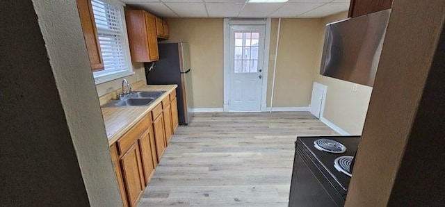 kitchen with sink, black electric range oven, stainless steel fridge, light hardwood / wood-style floors, and a drop ceiling