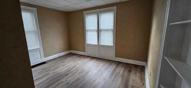 spare room with wood-type flooring and a drop ceiling