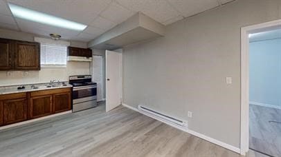 kitchen with a paneled ceiling, sink, light wood-type flooring, a baseboard radiator, and stainless steel range oven