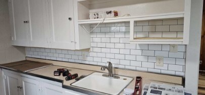 kitchen featuring white cabinets, backsplash, and sink