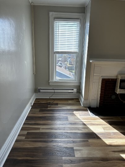 interior space with hardwood / wood-style floors, heating unit, crown molding, and a baseboard heating unit