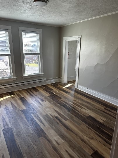 spare room featuring baseboard heating, dark hardwood / wood-style flooring, and a textured ceiling