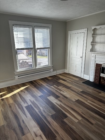 unfurnished living room with a textured ceiling, crown molding, and dark wood-type flooring