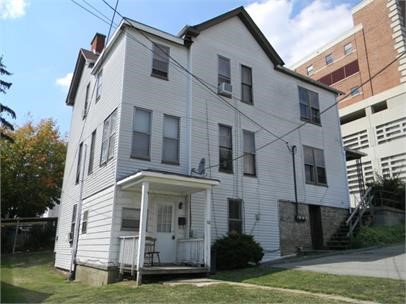 view of front of property featuring covered porch, a chimney, and a front yard