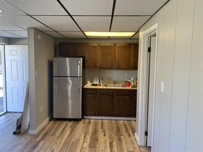 kitchen with stainless steel fridge, sink, and light hardwood / wood-style flooring