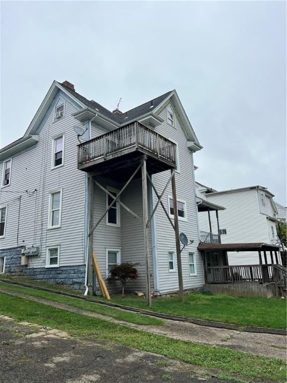 rear view of property with a balcony and a lawn