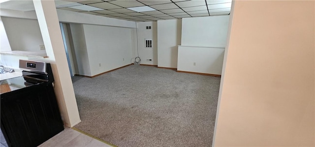 basement featuring a paneled ceiling and light colored carpet