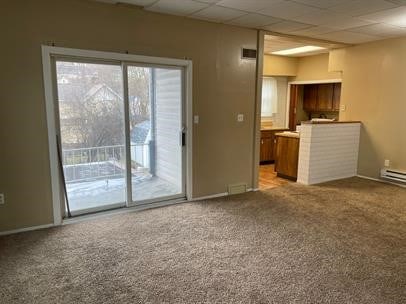 unfurnished living room with a paneled ceiling and light colored carpet