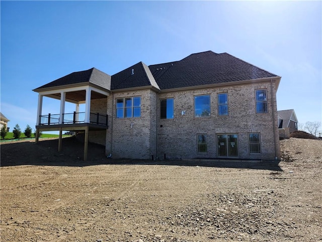 back of property with a shingled roof and brick siding