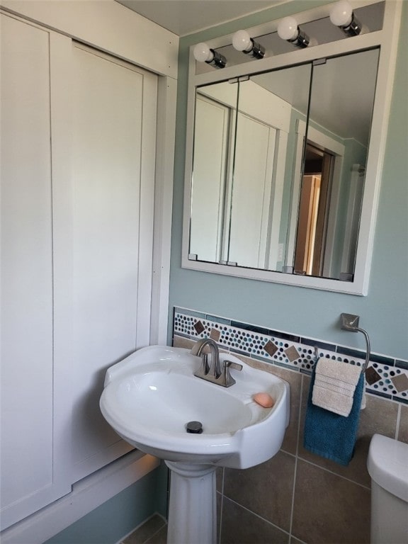 bathroom with toilet and tile walls