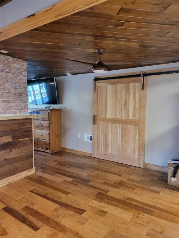 interior space featuring a barn door, light hardwood / wood-style floors, and wood ceiling