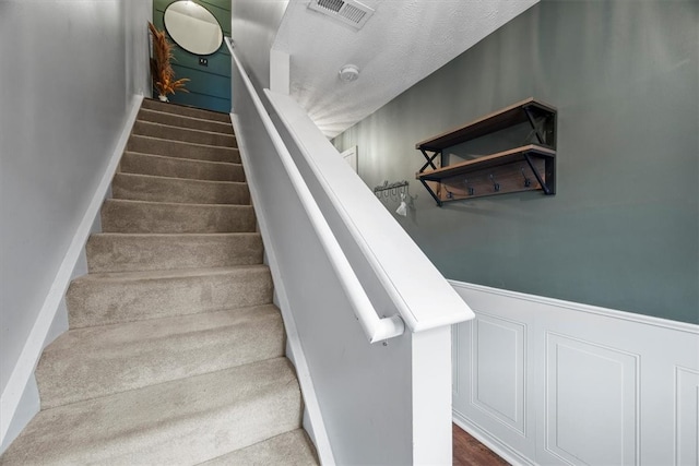 staircase featuring a textured ceiling