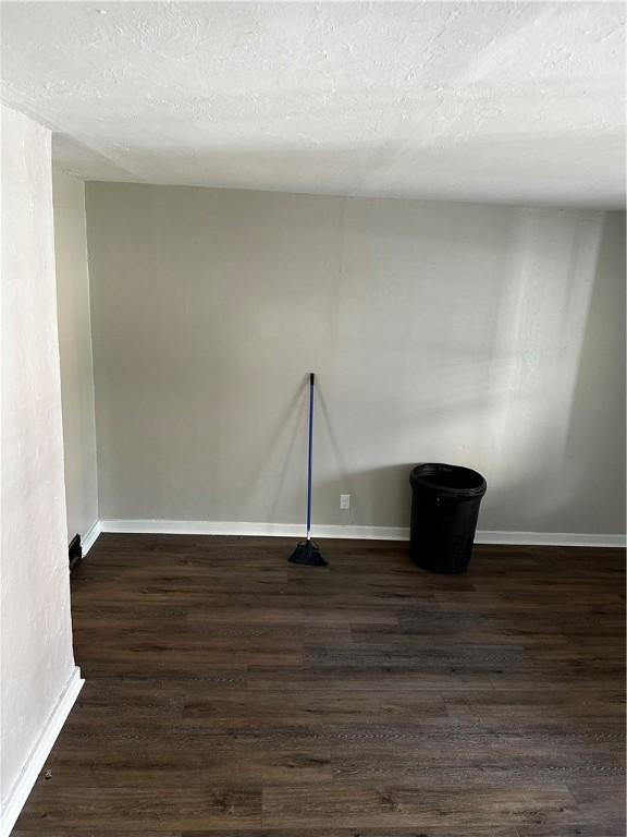 empty room featuring dark hardwood / wood-style floors and a textured ceiling