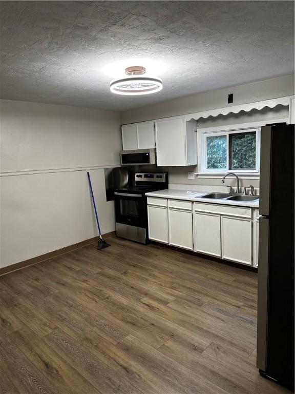 kitchen with sink, stainless steel appliances, dark hardwood / wood-style floors, a textured ceiling, and white cabinets