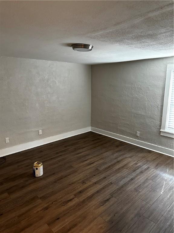 spare room featuring dark hardwood / wood-style floors and a textured ceiling