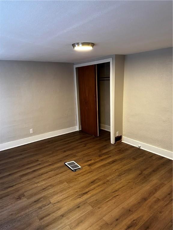 unfurnished bedroom with dark hardwood / wood-style floors and a closet