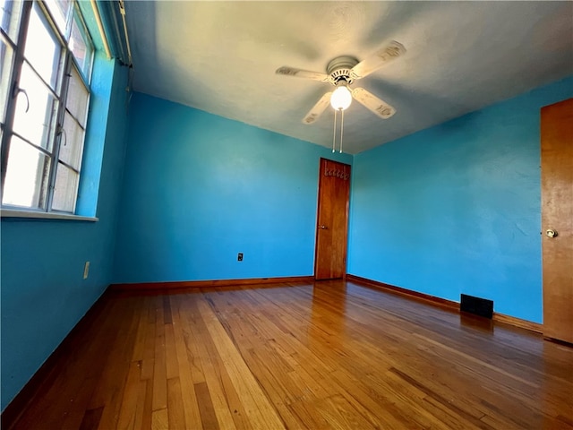 empty room with ceiling fan, hardwood / wood-style flooring, and a healthy amount of sunlight