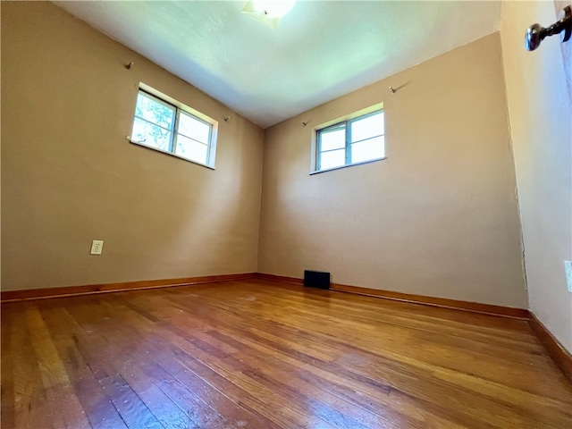 spare room with a wealth of natural light and hardwood / wood-style floors