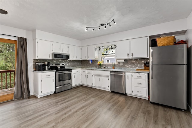 kitchen featuring appliances with stainless steel finishes, light wood-type flooring, white cabinetry, and a healthy amount of sunlight