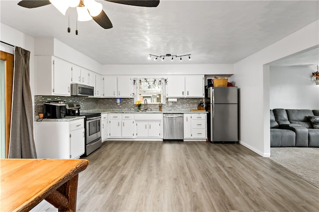 kitchen with decorative backsplash, light hardwood / wood-style floors, white cabinetry, stainless steel appliances, and sink