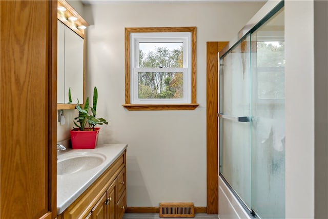 bathroom with vanity and bath / shower combo with glass door