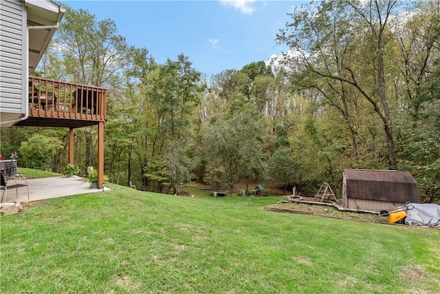 view of yard featuring a patio, a deck, and a shed