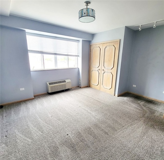 unfurnished bedroom featuring rail lighting, carpet flooring, and a wall mounted AC