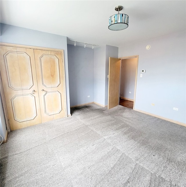 unfurnished bedroom with track lighting, light colored carpet, and a closet