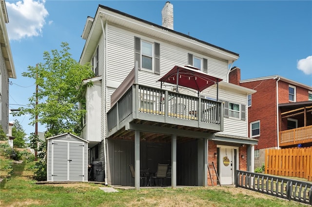 rear view of house featuring a storage shed, a yard, and a deck