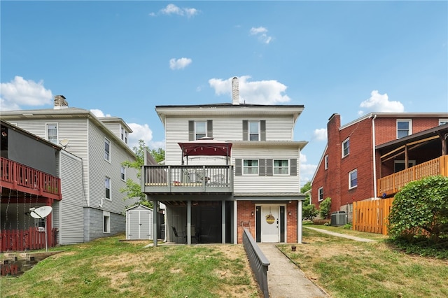 view of front facade featuring cooling unit, a shed, a front yard, and a deck