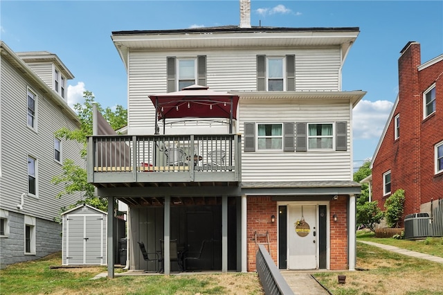 back of property featuring a storage shed, a yard, and a wooden deck