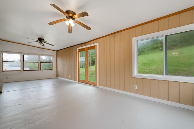 spare room with wooden walls, concrete floors, and ceiling fan