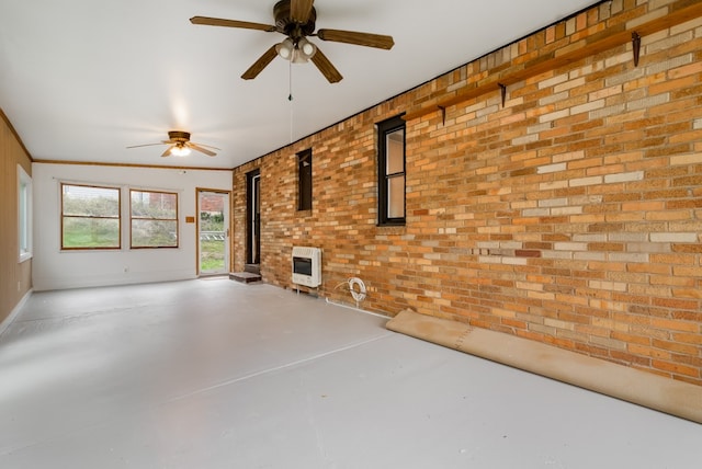 interior space featuring brick wall, concrete flooring, heating unit, and ceiling fan