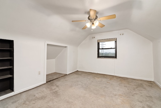 bonus room featuring vaulted ceiling, light carpet, built in features, and ceiling fan