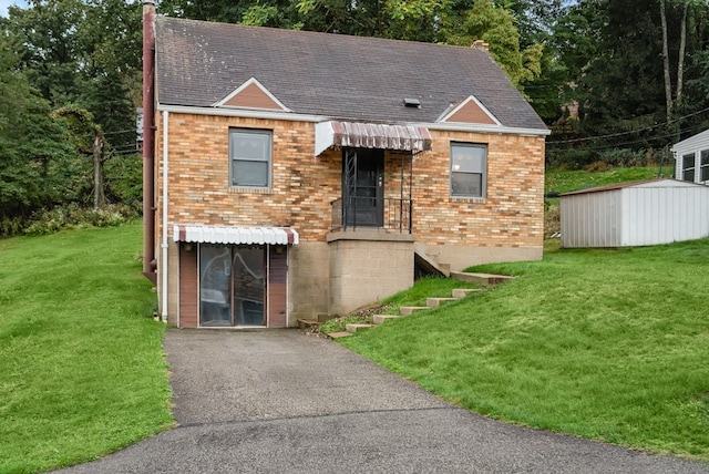 view of front of home with a storage shed and a front yard