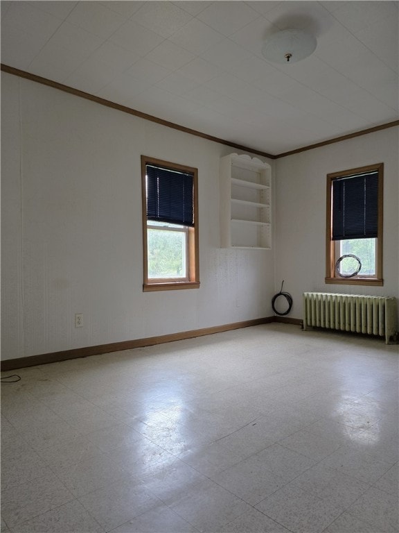 empty room featuring built in shelves, radiator, ornamental molding, and a healthy amount of sunlight