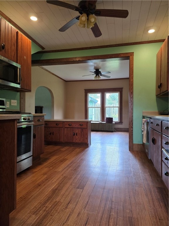 kitchen featuring ceiling fan, radiator, ornamental molding, appliances with stainless steel finishes, and dark hardwood / wood-style floors