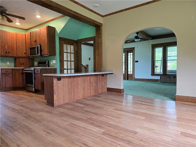 kitchen with appliances with stainless steel finishes, light hardwood / wood-style floors, a breakfast bar, kitchen peninsula, and radiator