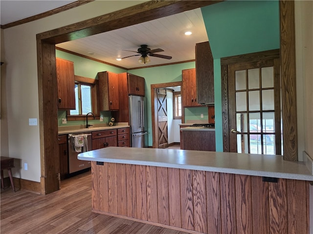 kitchen featuring light wood-type flooring, kitchen peninsula, appliances with stainless steel finishes, and ceiling fan